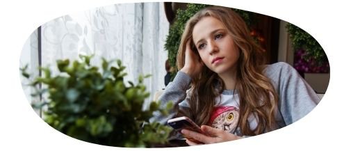 Girl sitting down with hand supporting head looking down