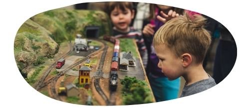 Young bog with blonde hair intently looking at a model railway